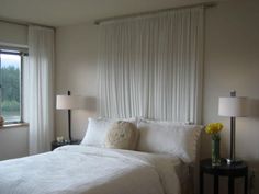 a white bed sitting in a bedroom next to two lamps on either side of a window