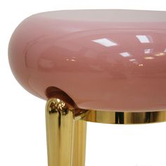 a pink glass table with gold legs on a white background