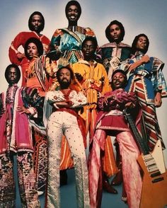 a group of people standing next to each other wearing colorful outfits and holding guitars in their hands