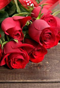 a bunch of red roses sitting on top of a wooden table