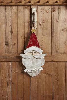 a santa clause mask hanging on the side of a wooden wall