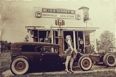 an old fashion photo of a woman standing in front of a store with antique cars