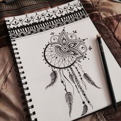 an open notebook with a drawing of a dream catcher on it and a pen next to it