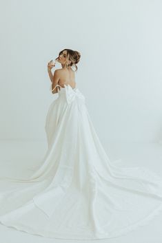 a woman in a white dress is posing for the camera with her back to the camera