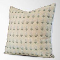 a white pillow with green and blue flowers on it