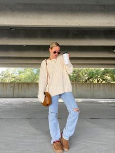 A girl is wearing a beige sweater and jeans. She’s posing in a parking lot. Fashion Trends Winter, Ugg Slippers, Winter Fits, Cozy Fits, Fall Fashion Trends, Light Wash Denim, Oversized Sweater, Baggy Jeans, Fashion Clothes