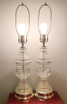 two clear glass lamps sitting on top of a red table