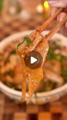 a person holding chopsticks over a bowl of food