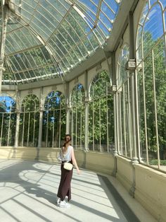 a woman is standing in an empty room with glass walls and windows on the ceiling