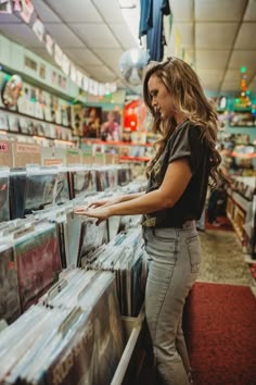 a woman looking at records in a record store aisle with the shelves full of cds