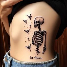 a woman with a skeleton tattoo on her stomach and the words let them fly above it