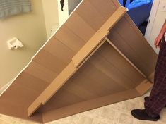 a man is standing next to a cardboard box that has been built into the floor