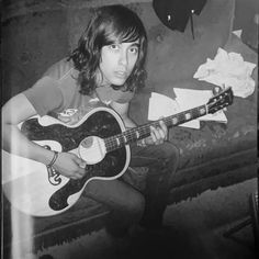 a young man sitting on a couch holding a guitar