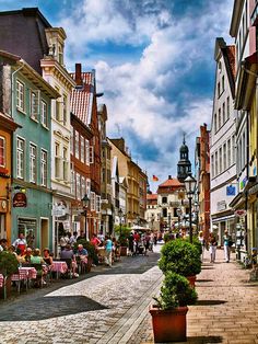 people are sitting at tables in the middle of an old town street with cobblestone streets