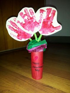 a red vase filled with pink flowers on top of a wooden floor