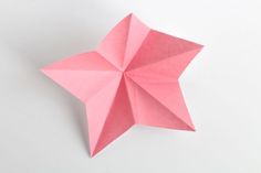 a pink origami star on a white background