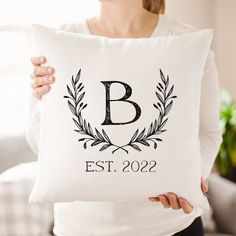 a woman holding a pillow with the letter b on it