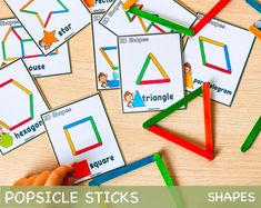 several popsicle stick shapes on a table with colored pencils in front of them