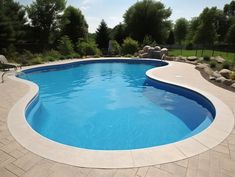 an empty swimming pool in the middle of a backyard with stone pavers around it