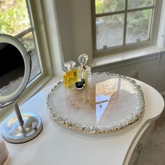 a table with a mirror and some bottles on it next to a window sill