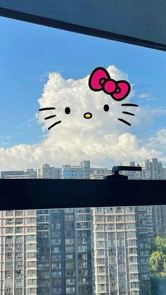 an image of a window with hello kitty sticker on the window sill and buildings in the background