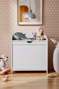 a white toy chest sitting on top of a hard wood floor next to a polka dot wall