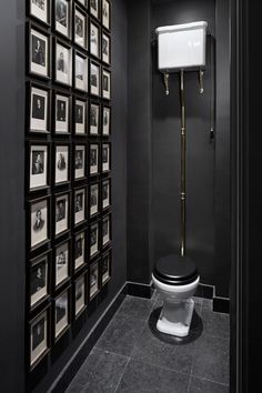 a black and white bathroom with pictures on the wall next to a toilet that is covered in photos