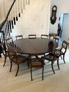 a dining room table with six chairs and a clock on the wall in front of it