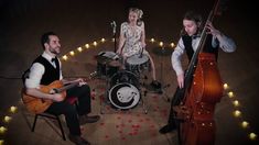 three people are playing instruments and singing in front of the camera while sitting on chairs