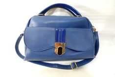 For sale is a women's blue leather pocketbook from Nila Anthony with convertible shoulder strap.  Nice simple design with a gold clasp with blue patent leather accent and on handles too.  It measures 13" across the bottom and a 9" height.  The sides are 5" wide.  Nice and roomy.  In excellent, like-new condition.  It was only used once or twice.  Perfect!   Lovely medium blue color. Pocket Book, Medium Blue, Blue Leather, Leather Backpack, Patent Leather, Bags Handbags, Leather Handbags, Shoulder Strap, Blue Color