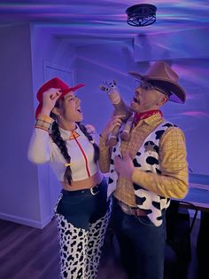 a man and woman dressed up as cowgirls singing into microphones in a room