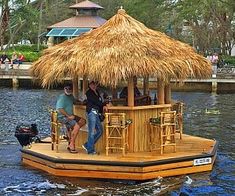 two people are standing on the deck of a house boat with thatched straw roof