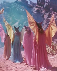 three women dressed in pink and yellow with bats on their heads