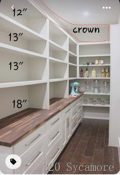 an empty walk in closet with white cabinets and wood counter tops on the bottom shelf