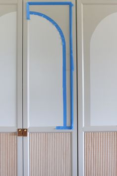 the door is painted white and has blue tape on it's side, as well as an arch