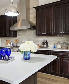 a white counter top in a kitchen with wooden cabinets and blue glassware on it