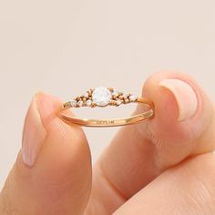 a woman's hand holding a gold ring with two diamonds on it and the middle finger