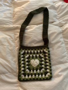 a crocheted bag sitting on top of a white bed next to a pillow