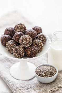 a white plate topped with chocolate covered donuts next to a bottle of almond milk