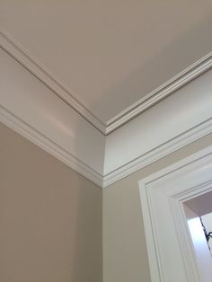 the corner of a room with a mirror and white trim on the wall above it