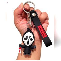 a hand holding a black and white keychain with a panda bear on it