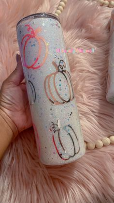 a hand holding a glittered tumbler with pumpkins and stars on the side