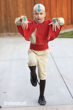 a young boy dressed in costume running on the sidewalk