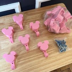 several pink mickey mouse shaped magnets are on a wooden table next to some plastic bags