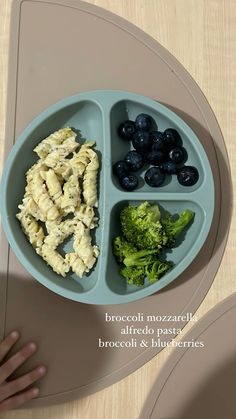 a child's plate with broccoli, blueberries and pasta in it