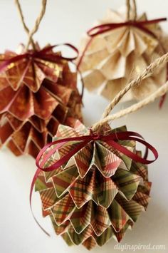 two paper pine cones with red ribbons tied to them, one is brown and the other is green