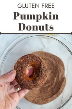 a hand holding a donut in a glass bowl with the words gluten free pumpkin donuts above it