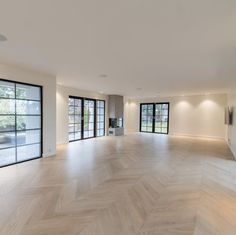 an empty room with wooden floors and large windows