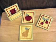 four cross stitch coasters with apples on them