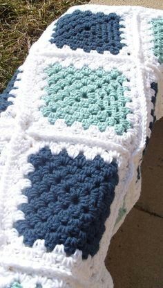 a crocheted blanket sitting on top of a sidewalk next to a brick wall